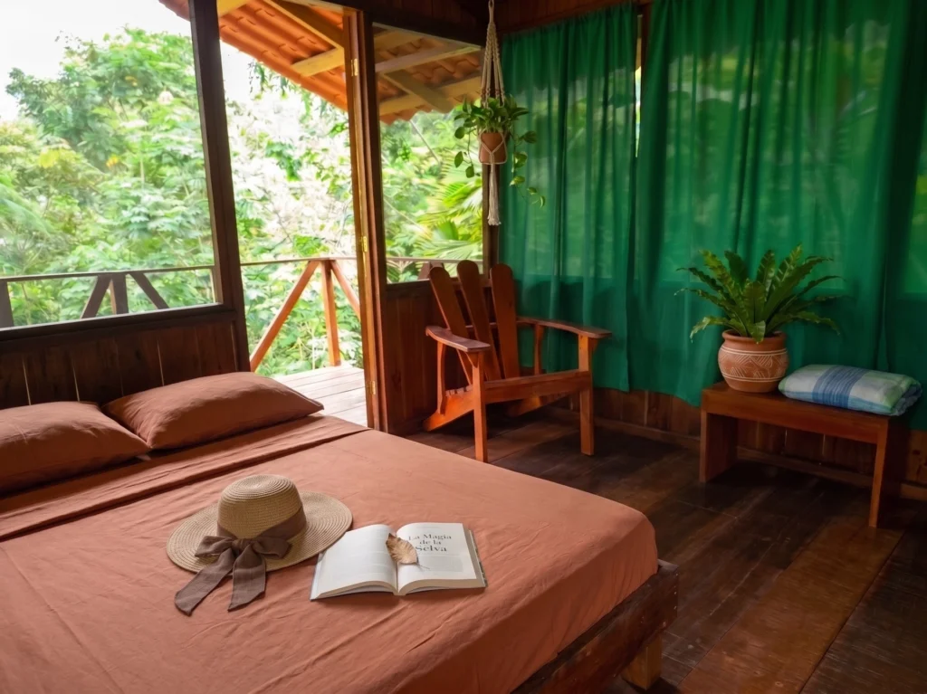 Pacuare River Ecolodge room with bed, chair, and greenery view