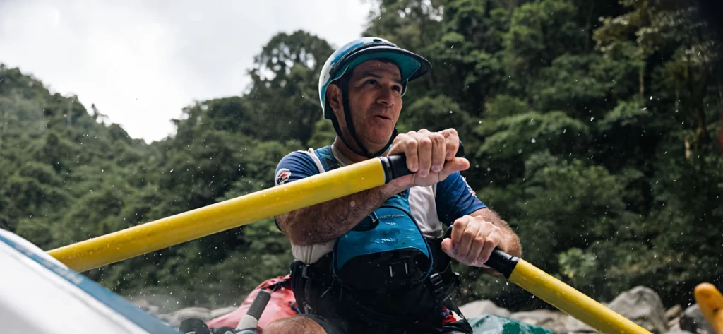 Pacuare River rafting guide navigating rapids with oars.