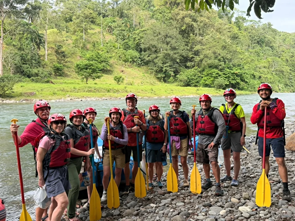 Pacuare River Ecolodge group rafting adventure, people with paddles and helmets